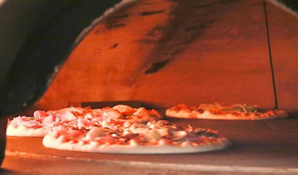 Trois pizzas qui cuisent côte à côte sur la sole du four